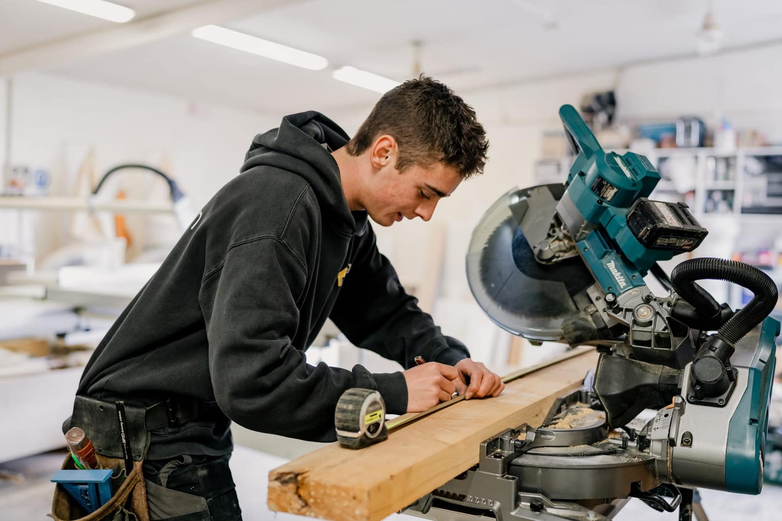 Luke measuring timber on the mitre saw in the Paragon Portables workshop